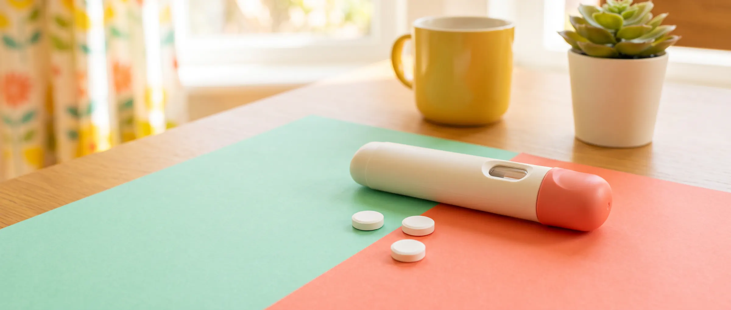 An injection pen next to a few tablets on a two-colour table